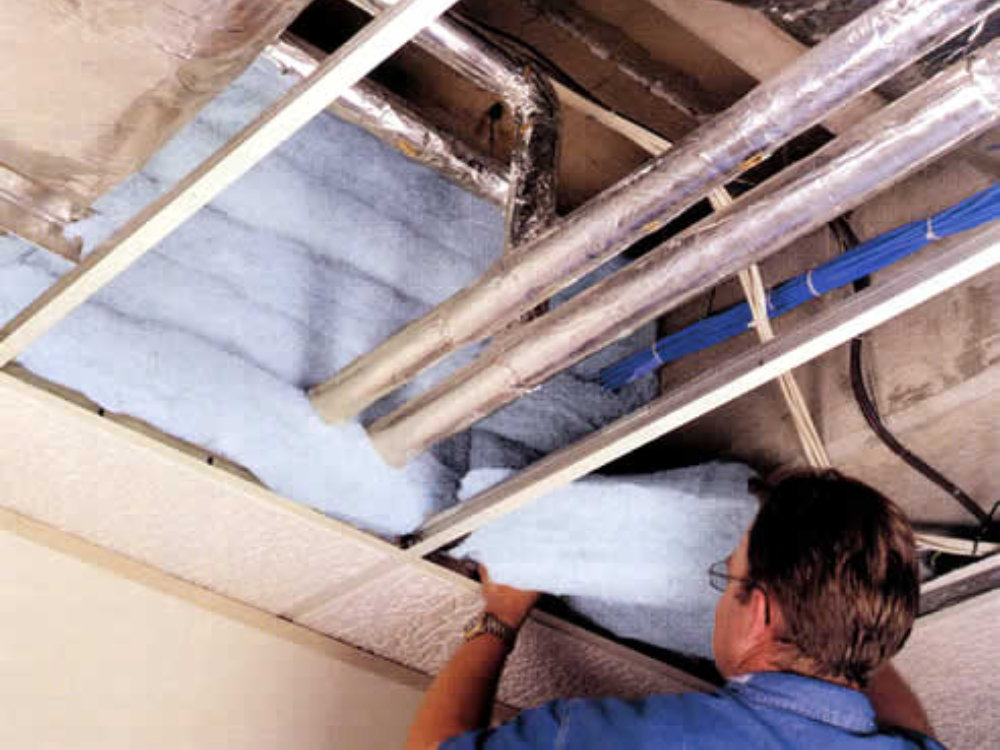 Man installing acoustic baffle into ceiling void