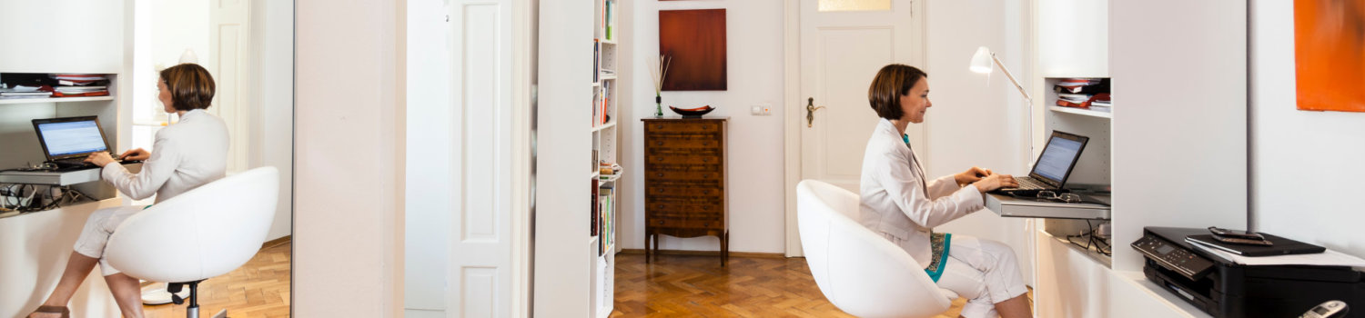 Mature businesswoman typing on laptop in apartment